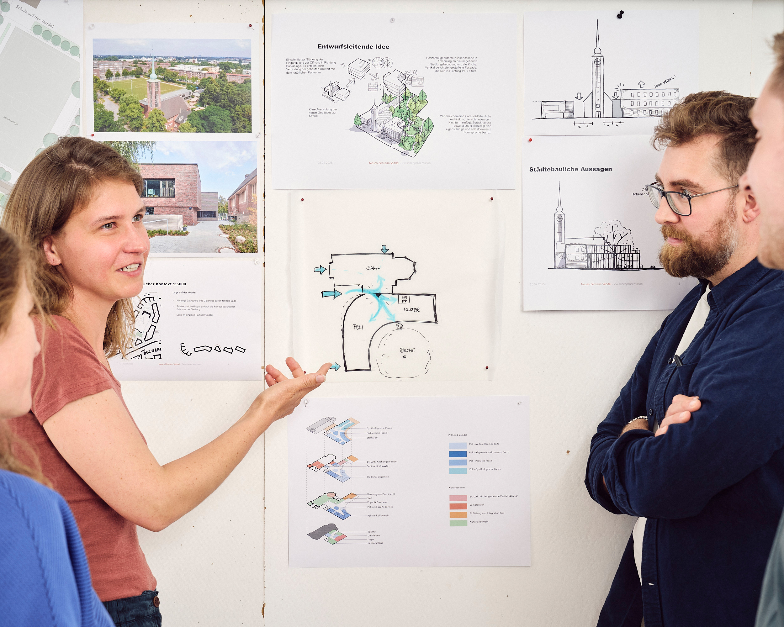 Eine kleine Gruppe Menschen steht vor einer Architekturzeichnung und diskutiert.