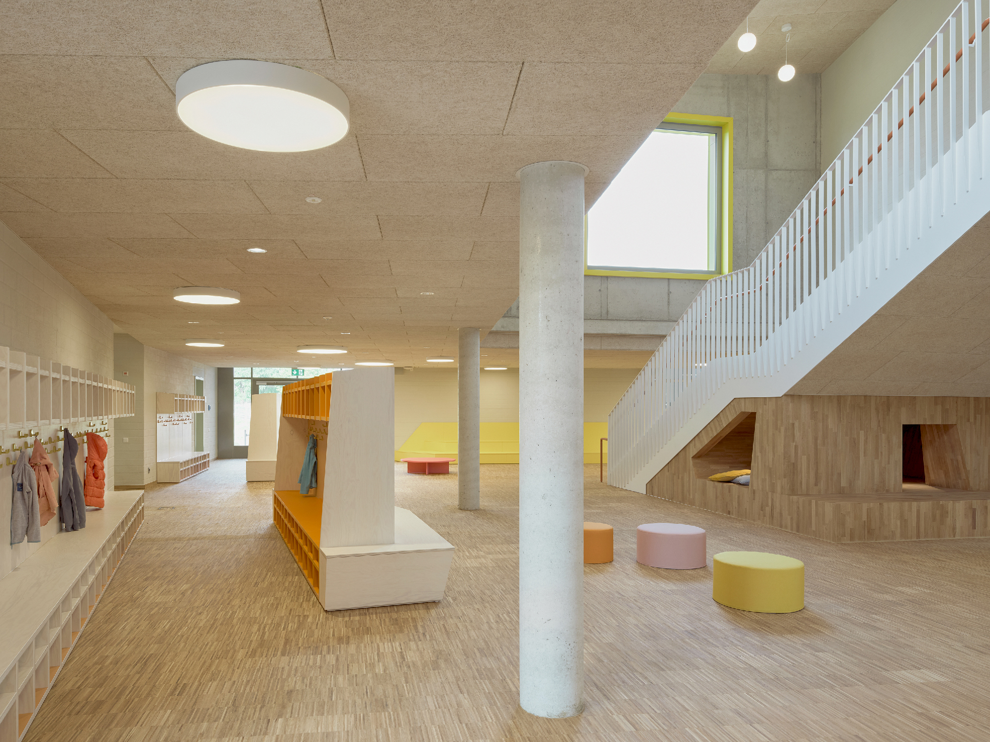 Innenraum einer Schule mit Treppe, Garderobenmöbel und Sitzmöglichkeiten