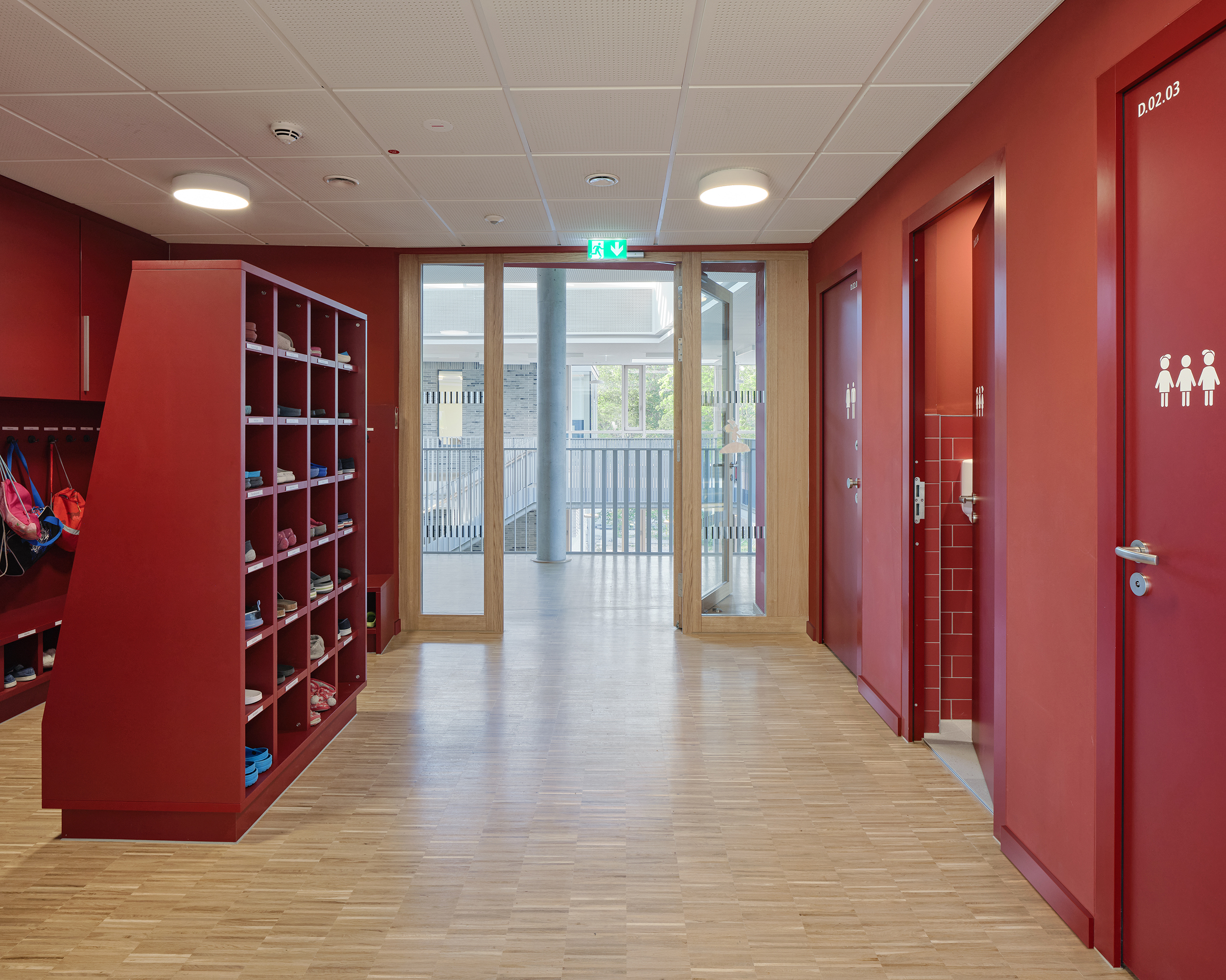 Kinder lernen auf einem mehrfach gefalteten Posest. Das Einbaumöbel aus Holz befindet sich auf der Galerie einer Schule.